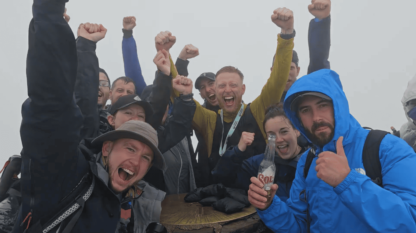 A group of people on top of a mountain with their arms raised.