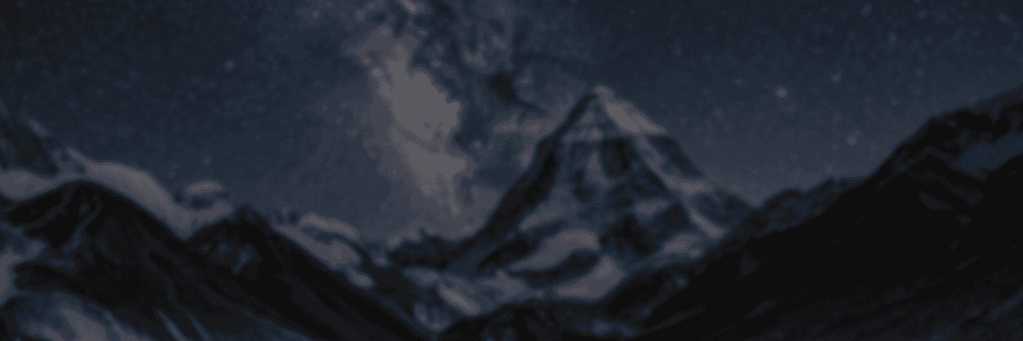 A snow-covered mountain peak under a night sky filled with stars and a visible section of the Milky Way.